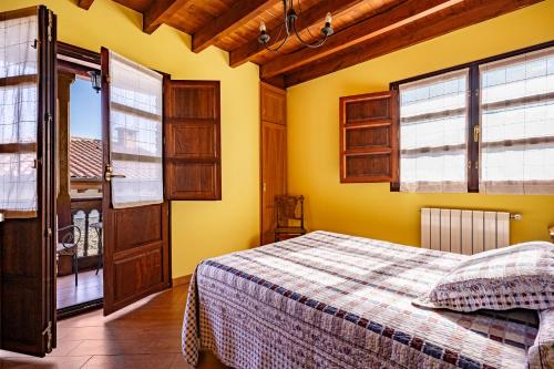 a bedroom with yellow walls and a bed and windows at Comeya in Cangas de Onís
