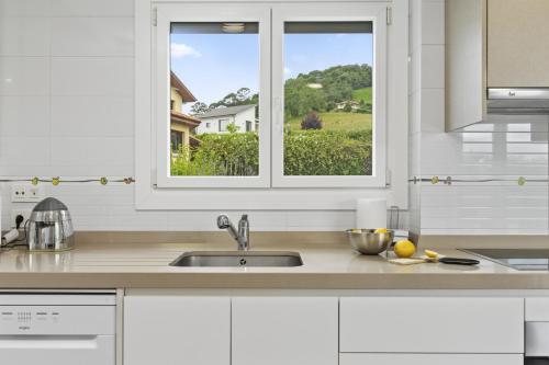 a white kitchen with a sink and a window at Casa La Manzana in Villaviciosa