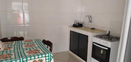 a kitchen with a stove and a sink and a table at Kitnet Encanto Astral in São Thomé das Letras