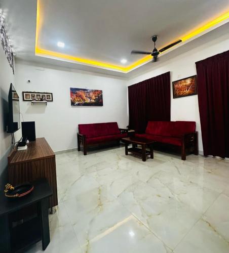 a living room with red couches and a tv at SK INN stays in Mahabalipuram