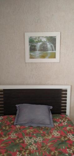 a bed in a bedroom with a picture on the wall at Kitnet Encanto Astral in São Thomé das Letras