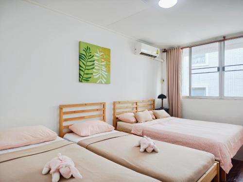 PratunamにあるThe Chan Vacation Homeのピンクのぬいぐるみが置かれたベッドが3つある部屋