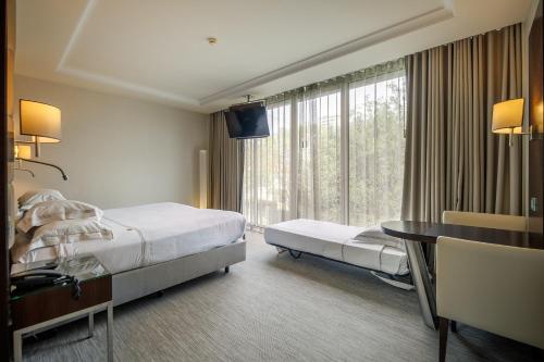 a hotel room with a bed and a desk and a window at BessaHotel Boavista in Porto