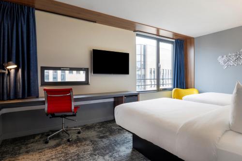 Habitación de hotel con escritorio y silla roja en Pestana Brussels Schuman, en Bruselas