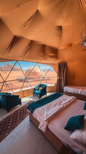 a large bed in a room with a large window at RUM FLORAA LUXURY CAMp in Wadi Rum