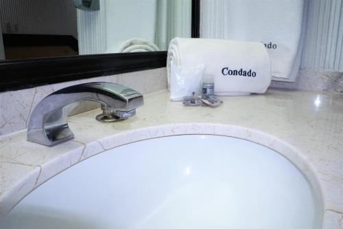 een badkamermeubel met een wastafel en een spiegel bij Hotel Condado in Mexico-Stad