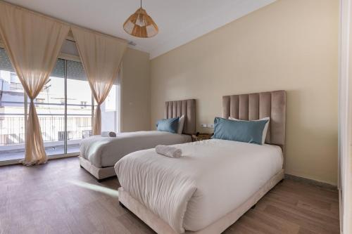 a bedroom with two beds and a large window at Élégant 2BR au cœur de Hassan by MERAT HOME in Rabat