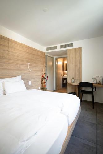 a bedroom with a large white bed and a desk at Locanda Marco in Bellinzona
