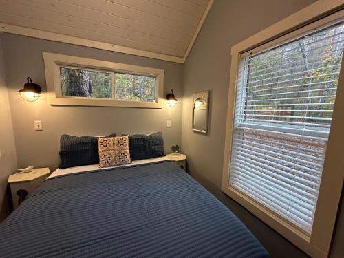 a bedroom with a blue bed and a window at Moon River Mentone 2-A Riverfront Tiny Home in Mentone