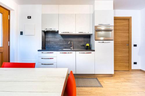 a kitchen with white cabinets and a sink and a table at Appartamenti Via Dell'Asilo in Isolaccia