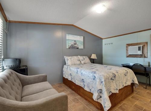 een slaapkamer met een bed, een bank en een stoel bij Fiddler's Restaurant and Resort in Steinhatchee