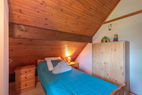 a bedroom with a blue bed with a wooden ceiling at Gîte sur les flancs du Hautacam in Artalens-Souin