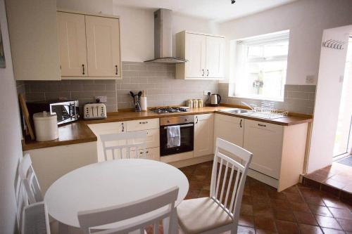 eine Küche mit einem weißen Tisch und Stühlen und einem Tisch und einem Tisch in der Unterkunft Stone's Throw // Central Newquay // Parking in Newquay