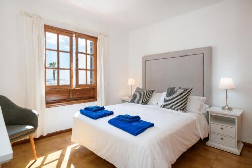 een slaapkamer met een groot wit bed met blauwe handdoeken bij Puerto Chico 7 in Playa Blanca