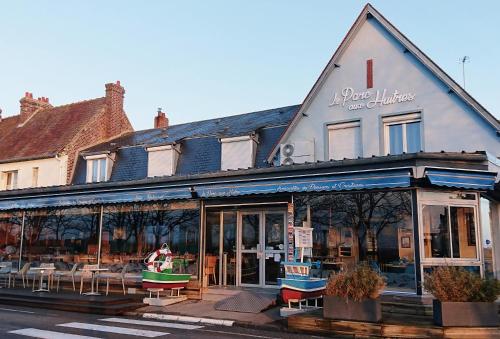 a building with tables and chairs in front of it at Le Parc aux Huîtres Hôtel Restaurant in Cayeux-sur-Mer