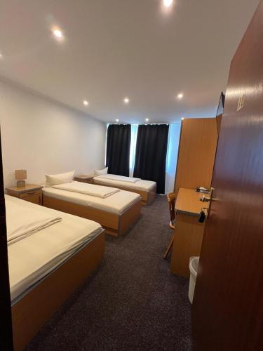 a hotel room with three beds and a desk at Hotel Dümptener Hof in Mülheim an der Ruhr