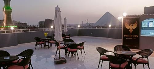 a rooftop patio with tables and chairs and a pyramid at Phoenix Pyramids View Inn in Cairo