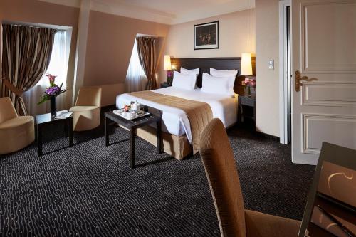 a hotel room with a large bed and a table at Hôtel Régent Contades in Strasbourg