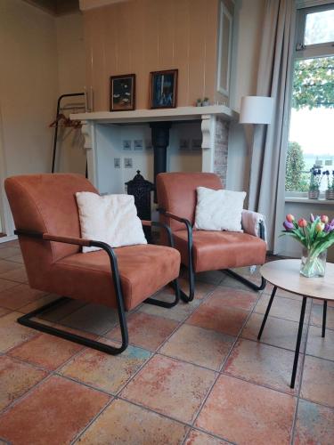 AkkrumにあるLuxe gastenverblijf met wellness in het hart van Frieslandのリビングルーム(椅子2脚、暖炉付)