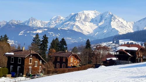 un groupe de maisons dans la neige avec des montagnes dans l'établissement Les Silenes, à Bellevaux