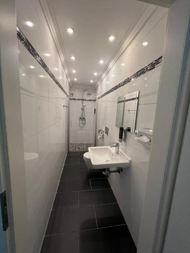 a white bathroom with a sink and a mirror at Hotel Dümptener Hof in Mülheim an der Ruhr