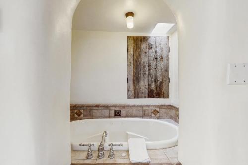 een wit bad in een badkamer met een spiegel bij Historic Hacienda in Ranchos de Taos