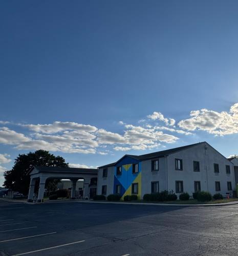 a white building with a blue roof next to a parking lot at Hotel Lincoln Inn on Route 66 and near I-55 in Lincoln