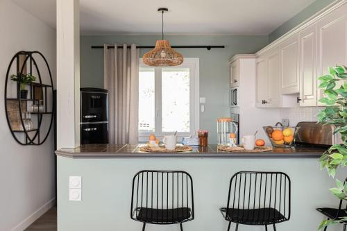 a kitchen with a counter with two black chairs at Le Cocon des Allamandières in Chonas-lʼAmballan