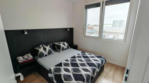 a bedroom with a black and white bed and a window at Sika Diplomat Apartment in Arad