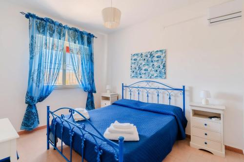 a blue bed in a white room with blue curtains at Fronte Mare Villa Raffaele in Punta Prosciutto