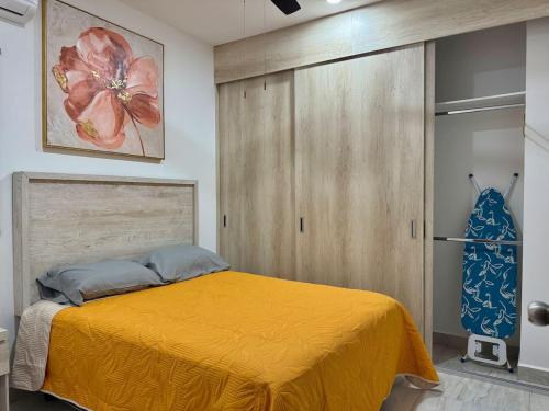 a bedroom with a yellow bed and a closet at Depa en el Centro Historico By GPSRentas in Isla Cardones