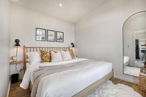 a white bedroom with a large bed and a mirror at Alpine Abode - Hot Tub, Nature in Brookville