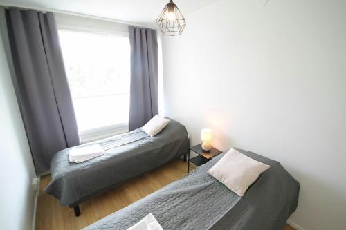 twee bedden in een kamer met een raam bij Convenient Apartment for 2 in Kouvola
