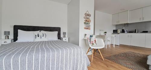 a white bedroom with a bed and a kitchen at Fascinante Orbita Apartments in Vila Nova de Famalicão