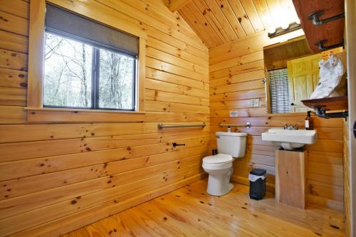 a log cabin bathroom with a toilet and a sink at Sanctuary Summit - Hot Tub in Brookville