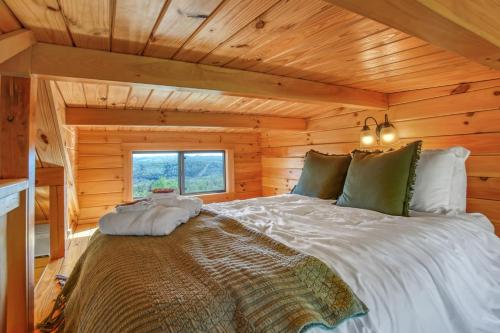 a bed in a log cabin with a window at Hillside Hideaway - Hot Tub in Brookville