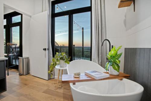 a bathroom with a white tub and a large window at Skyline Serenity - Hot Tub in Brookville