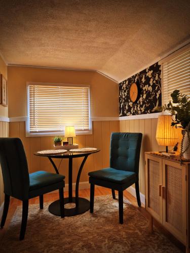 a room with two chairs and a table and a lamp at Parkview Boho Cottage 3 - Maple Meadows in Leamington