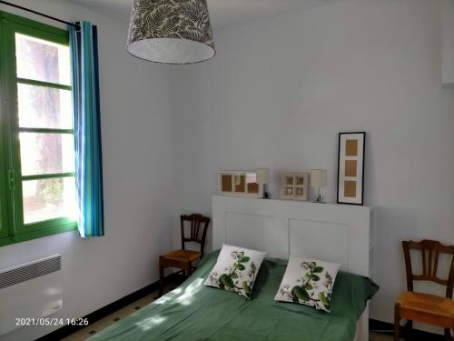 a bedroom with a green bed and a window at Le Landrin in Pénestin