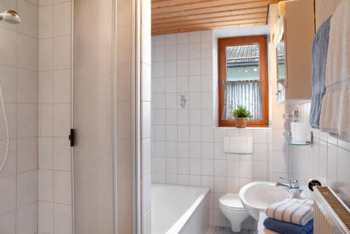 a bathroom with a tub and a toilet and a sink at Zum Schnitzer Franzl in Garmisch-Partenkirchen
