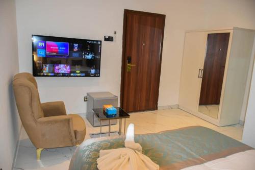 a living room with a couch and a tv on the wall at Viva Hôtel Ouaga 2000 in Ouagadougou