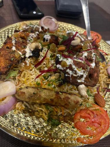 un plato de comida con carne y arroz en una mesa en Luxe Shalimaar, en Nueva Delhi