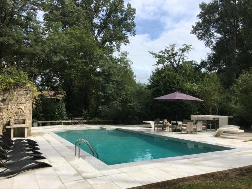 einen Pool mit einem Tisch und einem Sonnenschirm in der Unterkunft Idyllic Private Island Watermill Paradise in Roquebrune