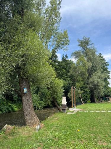 a tree with a sign on it next to a river at HALAL odmor - Villa Vrbas in Gornji Vakuf