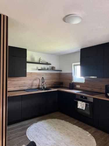 a kitchen with black cabinets and a sink at HALAL odmor - Villa Vrbas in Gornji Vakuf