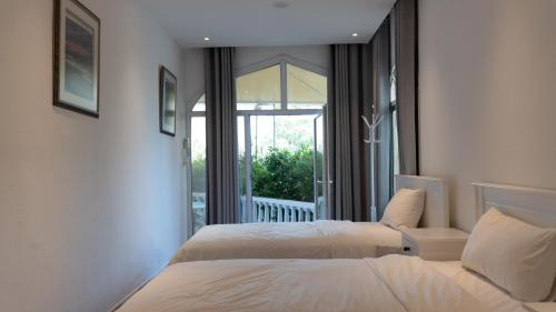 two beds in a hotel room with a balcony at بيت الشّاب in Ţīwī