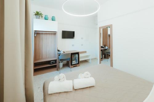 a white bedroom with two white towels on a bed at Verga 16 Deluxe Cefalù Apartments in Cefalù