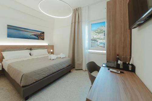 a bedroom with a bed and a table and a window at Verga 16 Deluxe Cefalù Apartments in Cefalù