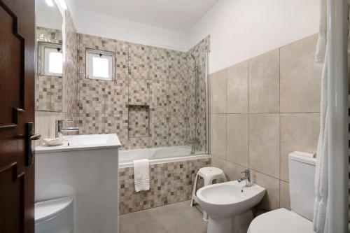 a bathroom with a sink and a toilet and a tub at Casa Harlequin in Vale do Lobo