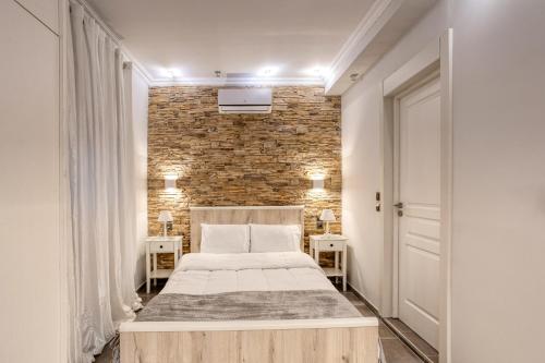 トリカラにあるWhite Houseのベッドとレンガの壁がある寝室